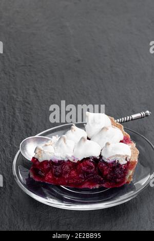 Meringue bedeckt Cranberry Torte Torte Scheibe auf schwarzem Stein Hintergrund Stockfoto