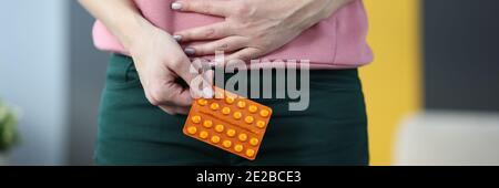 Frau mit Pillen in den Händen halten Unterbauch zu Hause Nahaufnahme Stockfoto