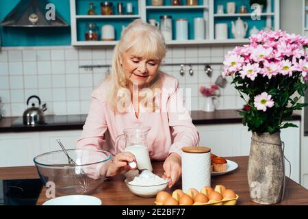 Cincematic Bild einer älteren Frau Backen und Kochen von Lebensmitteln in ihrer schönen Küche. Großmutter bereitet Kuchen und Süßigkeiten für die Danksagung vor Stockfoto