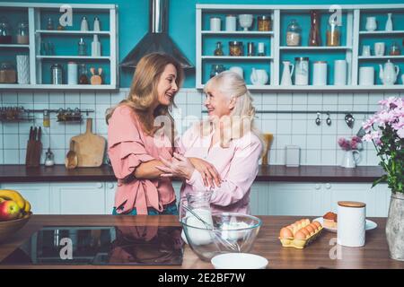 Cincematic Bild von einer älteren Frau und ihre Tochter Backen und Kochen Essen in ihrer schönen Küche. Großmutter bereitet Kuchen und Süßigkeiten für die Stockfoto