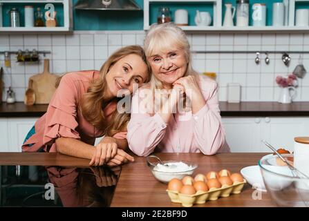 Cincematic Bild von einer älteren Frau und ihre Tochter Backen und Kochen Essen in ihrer schönen Küche. Großmutter bereitet Kuchen und Süßigkeiten für die Stockfoto