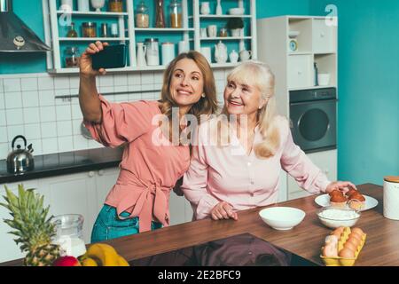 Cincematic Bild von einer älteren Frau und ihre Tochter Backen und Kochen Essen in ihrer schönen Küche. Großmutter bereitet Kuchen und Süßigkeiten für die Stockfoto