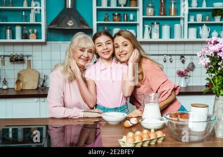 Cincematic Bild von einer älteren Frau und ihrer Tochter und Enkelin Backen und Kochen Essen in ihrer schönen Küche. Großmutter bereitet Kuchen und Stockfoto