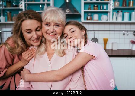 Cincematic Bild von einer älteren Frau und ihrer Tochter und Enkelin Backen und Kochen Essen in ihrer schönen Küche. Großmutter bereitet Kuchen und Stockfoto