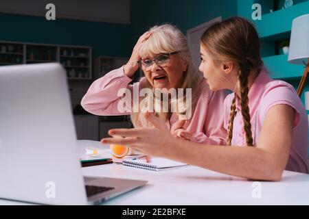 Filmisches Bild einer Großmutter und einer Enkelin, die zusammen Hausarbeiten machen. Mutter, die dem Kind hilft, das von zu Hause studiert, während 2020 die Sperre Stockfoto