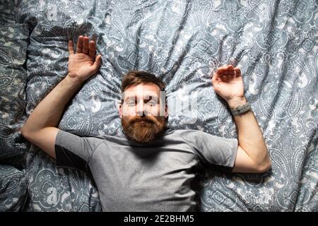 Schöner Mann, der sich im Bett erholte und den Blick von oben träumte Stockfoto