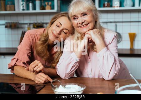 Cincematic Bild von einer älteren Frau und ihre Tochter Backen und Kochen Essen in ihrer schönen Küche. Großmutter bereitet Kuchen und Süßigkeiten für die Stockfoto