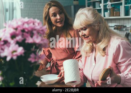 Cincematic Bild von einer älteren Frau und ihre Tochter Backen und Kochen Essen in ihrer schönen Küche. Großmutter bereitet Kuchen und Süßigkeiten für die Stockfoto