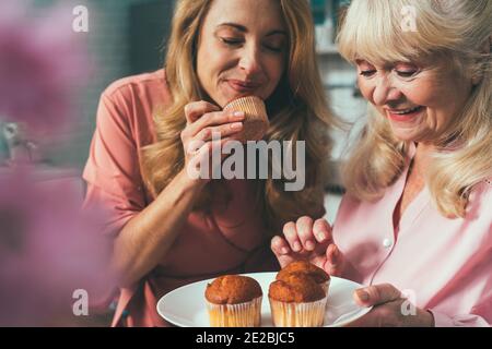 Cincematic Bild von einer älteren Frau und ihre Tochter Backen und Kochen Essen in ihrer schönen Küche. Großmutter bereitet Kuchen und Süßigkeiten für die Stockfoto