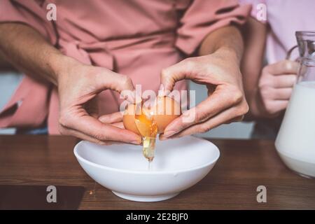 Cincematic Bild von einer älteren Frau und ihrer Tochter und Enkelin Backen und Kochen Essen in ihrer schönen Küche. Großmutter bereitet Kuchen und Stockfoto