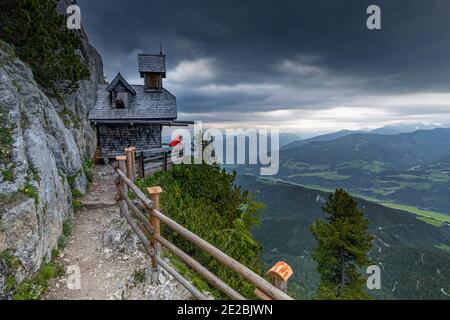 Tourist in der kleinen Friedenskapelle mit Blick über das Tal bei Stoderzinken, Gröbming, Kreis Liezen in der Steiermark, Österreich Stockfoto