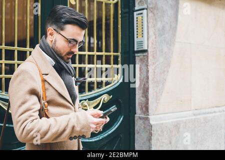 Elegante junge Mann in Dandy Stil Mode mit dem smart Telefon auf der Straße Stockfoto