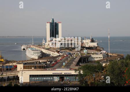 Blick auf den Hafen von Odessa in der Ukraine, mit Schiffen, Seeterminal und einem (ehemaligen) Hochhaus-Hotel. Im Hintergrund ist das Schwarze Meer zu sehen. Stockfoto