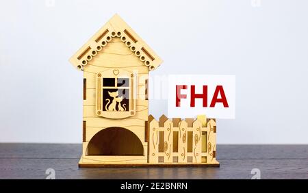 FHA, Bundeswohnungsverwaltung Symbol. White Paper mit dem Wort 'FHA, Federal Housing Administration' in der Nähe von Miniaturhaus. Schöne weiße Backgrou Stockfoto