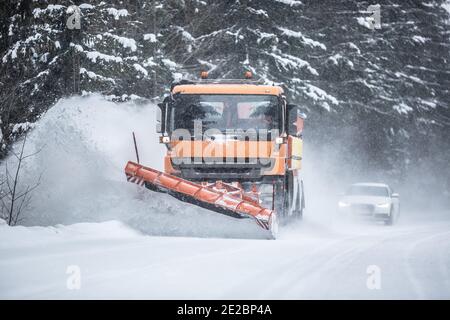 Schneepflug Clearing Straße von Schnee im Wald mit Verkehr Schlange sich hinter dem LKW. Stockfoto