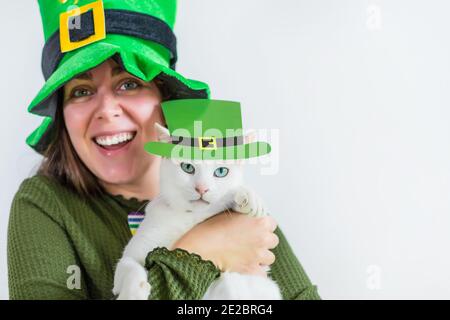 Mädchen in Saint Patrick's Day Kobold Party Hut, hält eine Katze mit Kobold Hut Stockfoto