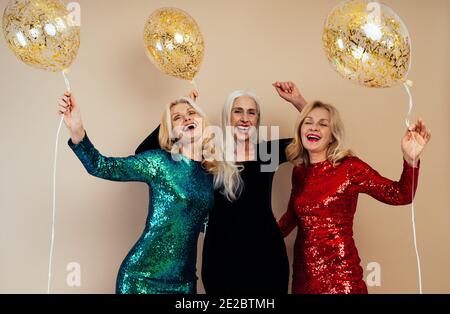 Schöne ältere Frau macht Party und feiert Neujahr. Frauen mittleren Alters tragen elegante glitzernde Kleider und Spaß haben. Studio Portraits ein Stockfoto