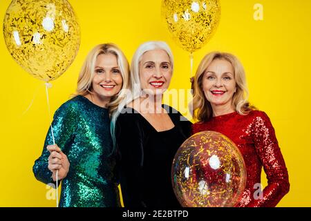 Schöne ältere Frau macht Party und feiert Neujahr. Frauen mittleren Alters tragen elegante glitzernde Kleider und Spaß haben. Studio Portraits ein Stockfoto
