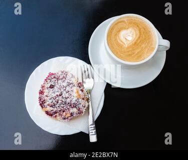 Öffnen Sie süß portionierten Kuchen mit Beeren. Köstliches Dessert auf einem Teller und eine Tasse Kaffee mit Milch Stockfoto