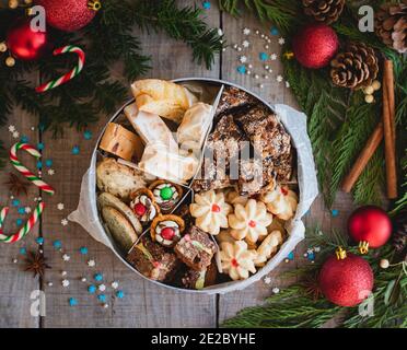 Blick von oben auf die runde Dose mit weihnachtskeksen mit festlicher Einrichtung. Stockfoto