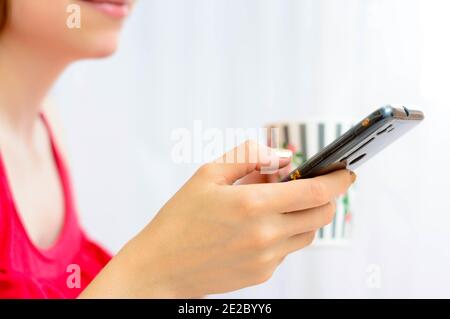 Frau mit Brille hält Tasse und ein Handy Stockfoto