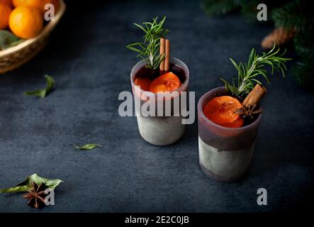 Glühwein in Gläsern mit Gewürzen, Rosmarin, Zimt und Orangen Stockfoto