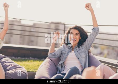 Schöne stilvolle fröhliche Gesellschaft sitzt in Tasche Stühle steigen Hände Up jubelte viel Glück Fortschritt auf dem Dach draußen draußen Sonniger Tag Stockfoto