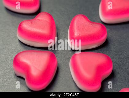 Nahaufnahme von rosa und weißen herzförmigen Süßigkeiten auf Eine graue Papieroberfläche Stockfoto