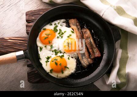 Rühreier und Speck in einer kleinen Pfanne auf dem Küchentisch Stockfoto