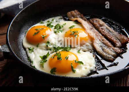 Rühreier und Speck in einer kleinen Pfanne auf dem Küchentisch Stockfoto