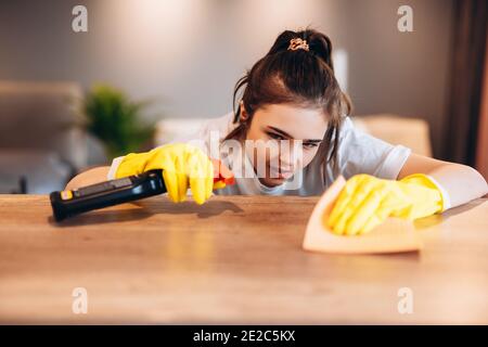 Close up glückliche Frau in gelben Handschuhen Reinigungstisch bei Home Küche mit Reinigungsmittel Stockfoto