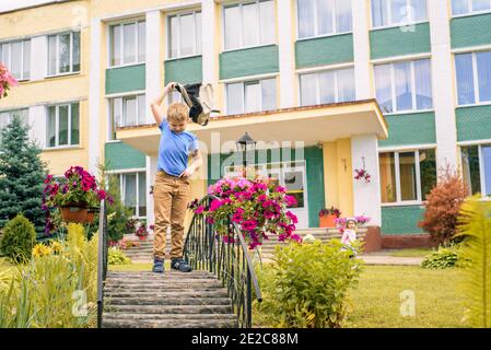 Porträt eines Schulkindes mit Rucksack springen . der Junge läuft einen Rucksack rund um den Schulhof.Kindheit, Bildung Lernkonzept Stockfoto