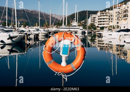 Eine Nahaufnahme einer Rettungsboje auf einem Stand auf dem Dock mit Blick auf die Berge und Yachten auf dem Wasser. Marina für Yachten in Montenegro, in Tivat, in der Nähe Stockfoto