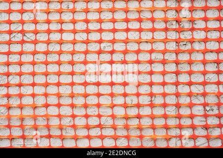 Textur Orange Zaun Konstruktion Mesh Nahaufnahme auf einem grauen Hintergrund. Stockfoto