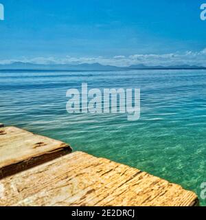 Landschaftsansicht entfernter Berge über klares, türkisfarbenes Wasser des Mittelmeers auf Mallorca, Spanien an einem hellen und sonnigen Tag. Stockfoto
