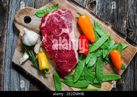 Rinderrippe Club Steak Boneles auf Schneidebrett mit Gemüse Stockfoto