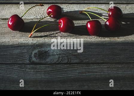 Kirschen in einer Reihe auf Holztisch in A angeordnet Lichtstreifen Stockfoto