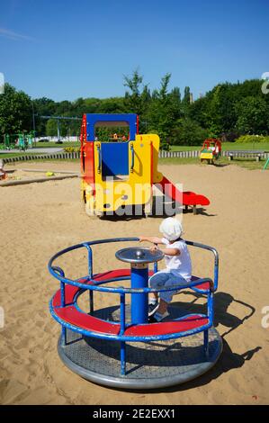 POZNAN, POLEN - 19. Jul 2017: Kind im Kreisverkehr eines Spielplatzes im Jan Pawla Park an einem warmen Sommertag. Stockfoto