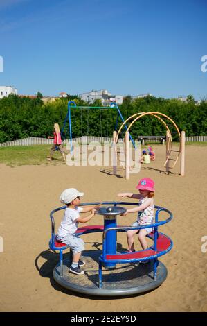 POZNAN, POLEN - 19. Jul 2017: Kinder im Kreisel eines Spielplatzes im Jan Pawla Park an einem warmen Sommertag. Stockfoto