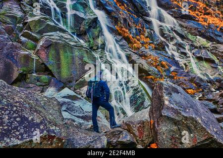 Junger Mann bewundert die Wasserfälle von Nardis im Val di Genova, Naturpark Adamello-Brenta in Norditalien Stockfoto