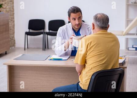 Alter Hals verletzten Mann besucht jungen Arzt Stockfoto
