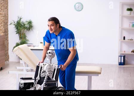 Männlicher Arzt und Skelett im Rollstuhl Stockfoto