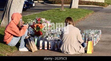 FRESNO, USA - 30. Dez 2020: Ein Foto von zwei trauernden Jugendlichen, die neben Kerzen und Blumen für die Opfer saßen, die an einem tödlichen Auto starben Stockfoto