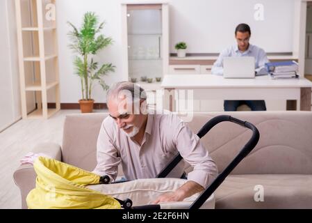 Alter Großvater, der sich zu Hause um das Neugeborene gefreut hat Stockfoto