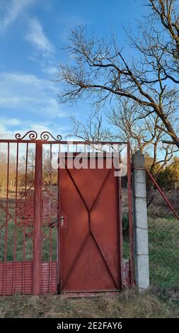 Vertikale Aufnahme eines rot geschweißten Tores in einer Farm Stockfoto