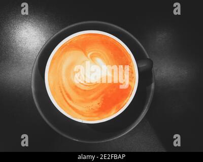 Nahaufnahme eines Kaffee Latte Art mit herzförmigen in Eine schwarze Tasse und Untertasse Stockfoto