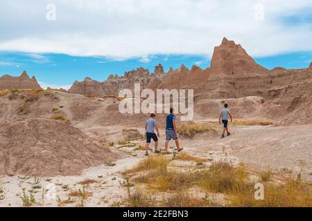 Unerkennbare junge Männer wandern zwischen den Felsformationen des Badlands National Park, South Dakota, USA (Vereinigte Staaten von Amerika). Stockfoto