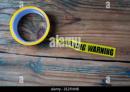 Warnband auf einem Holztexturtisch. Information, Eindämmung und Verbot. Stockfoto