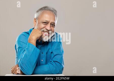 EIN ERWACHSENER MANN, DER DIE KAMERA ANSCHAUT UND LÄCHELT Stockfoto