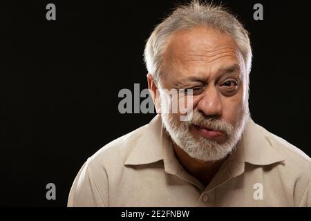 EIN ÄLTERER ERWACHSENER MANN, DER DIE KAMERA ANSAH UND ZWINKELTE Stockfoto